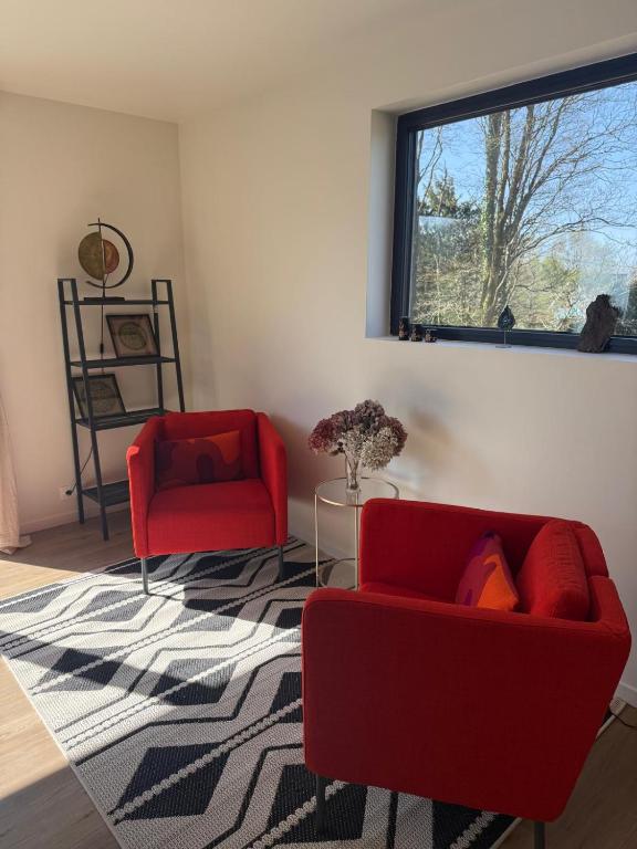 a living room with two red chairs and a window at Studio neuf dans un espace boisé in Locronan
