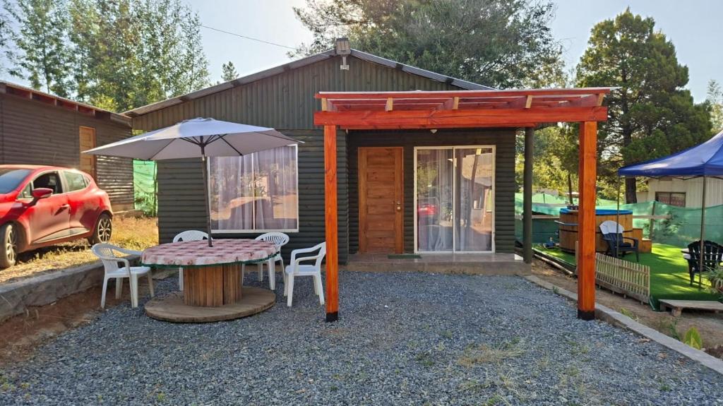 un patio con una mesa y una sombrilla en Refugio Vilches, en Vilches