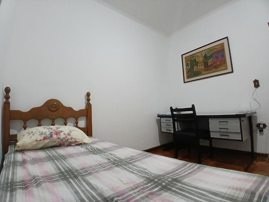 a bedroom with a bed and a desk with a picture at Home office solteiro aconchegante no Centro de Poços de Caldas in Poços de Caldas