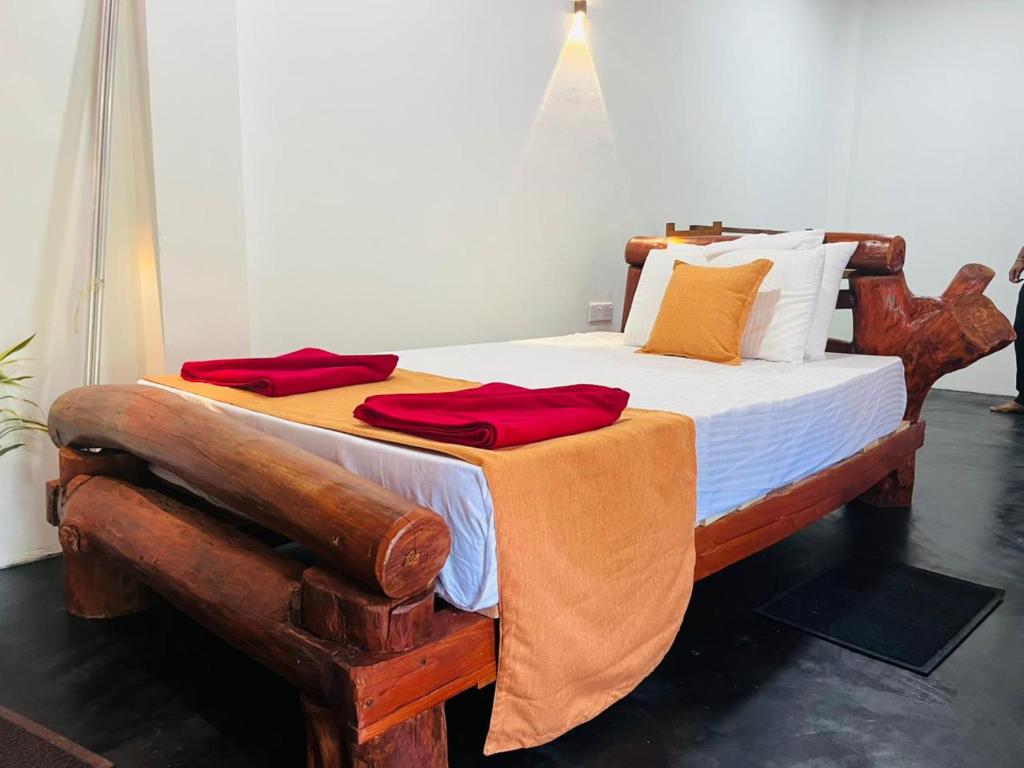 une chambre avec un lit en bois recouvert de serviettes rouges dans l'établissement Ella EDAN Homestay, à Ella