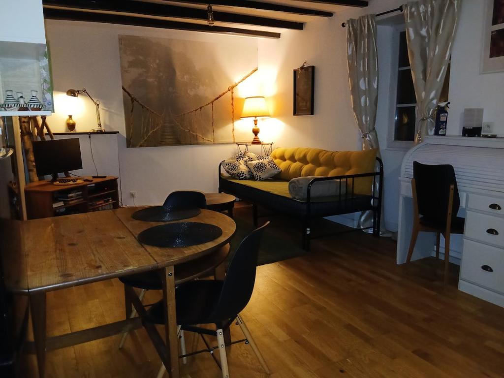 Una sala de estar con un sofá amarillo y una mesa. en Studio indépendant T1, entre Nantes et Rennes, en Conquereuil