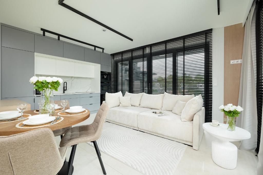 ein Wohnzimmer mit einer weißen Couch und einem Tisch in der Unterkunft Apartment Sea Light - Best Comfort - by rentmonkey in Pogorzelica