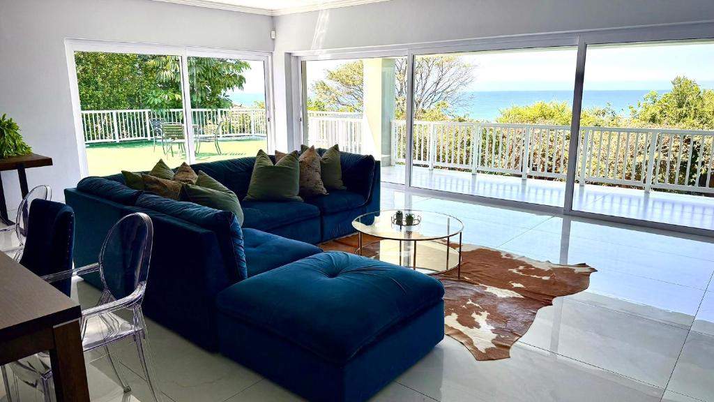 a living room with a blue couch and large windows at Gemmel Place Villa in Durban