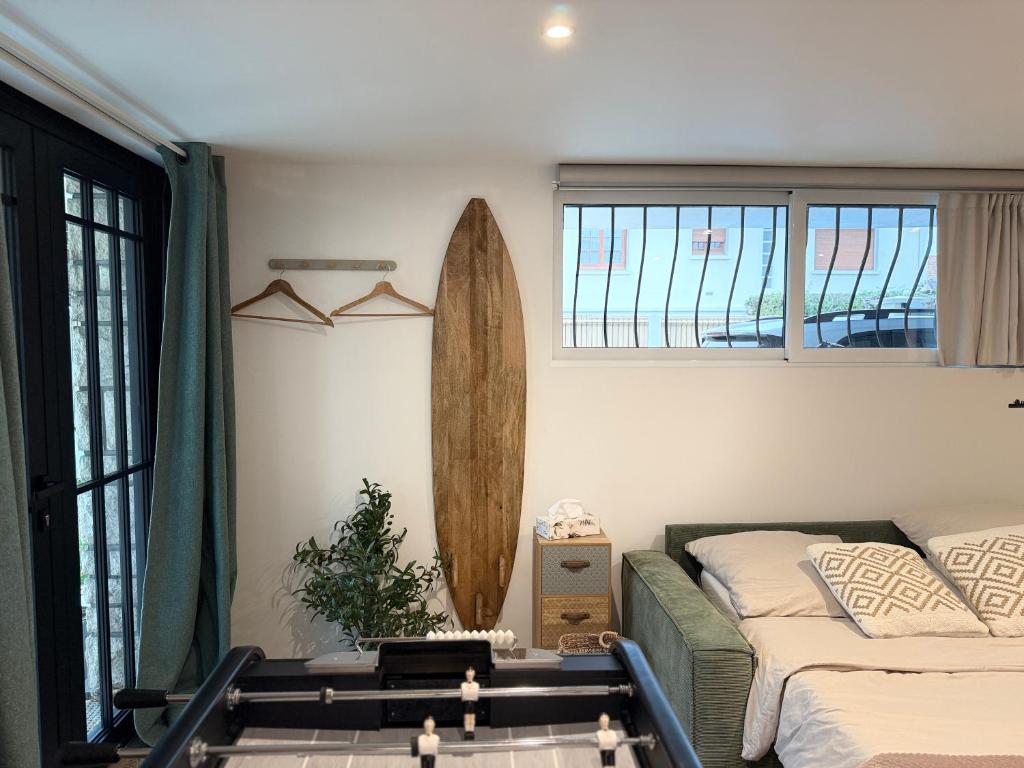 Un dormitorio con una cama y una tabla de surf en la pared. en Superbe studio neuf & design - 20 min Versailles, en Les Clayes-sous-Bois