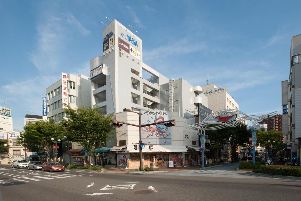 un edificio blanco alto en una calle de la ciudad con un semáforo en Hotel Yassa en Mihara