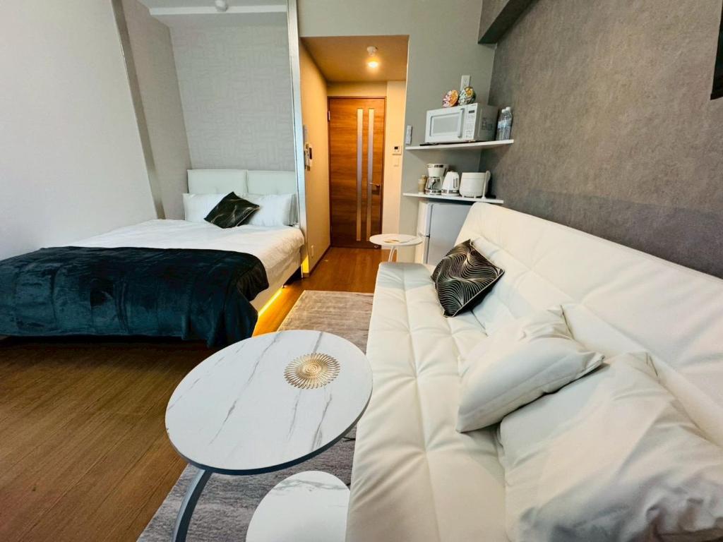 ein Wohnzimmer mit einer Couch und einem Bett in der Unterkunft LuxurySweet 博多駅南53 in Fukuoka