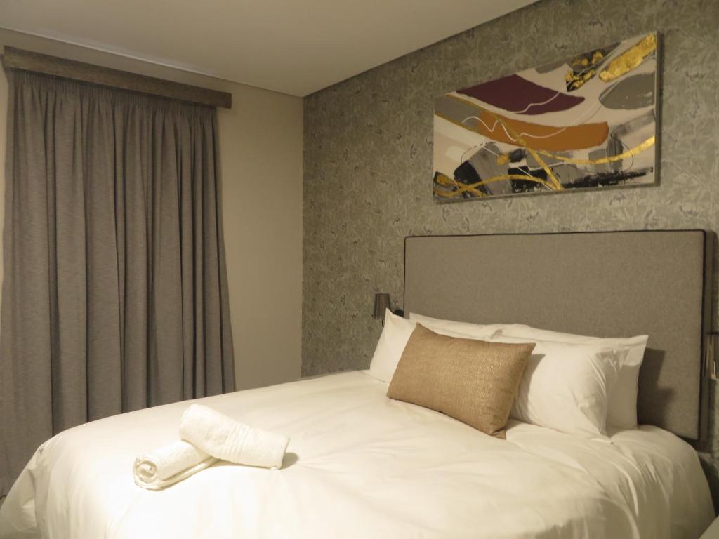 a bedroom with a large white bed with a cross on it at Eden Hotel on Florida in Durban