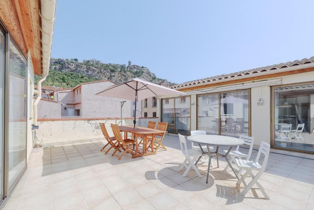 a patio with a table and chairs and an umbrella at Gîtes Tautavel in Tautavel