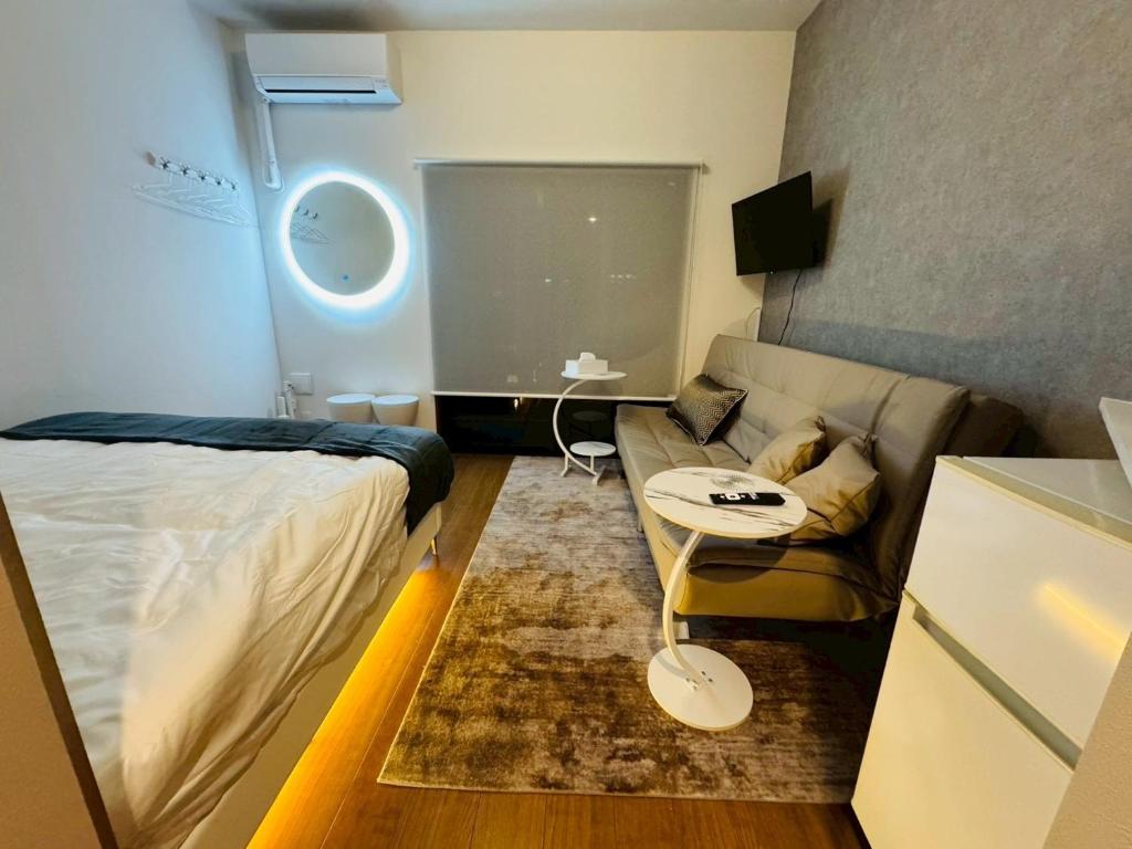 ein kleines Zimmer mit einem Bett und einer Couch in der Unterkunft LuxurySweet 博多駅南62 in Fukuoka
