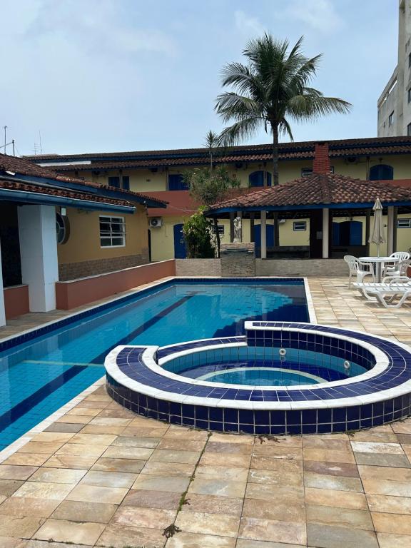 a swimming pool in the middle of a courtyard with a house at Villa Di Verona Charm Hotel in Guarujá