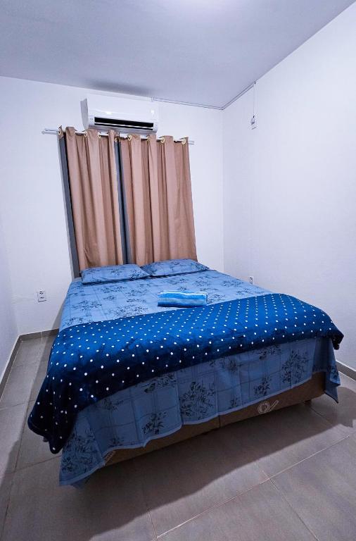 a bedroom with a bed with a blue comforter and a window at Aconchego na Chapada in Lençóis