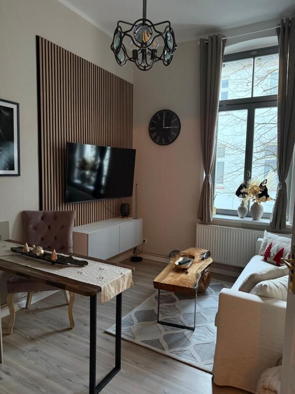 ein Wohnzimmer mit Tisch und Fernseher in der Unterkunft Apartment Baltica in Rostock