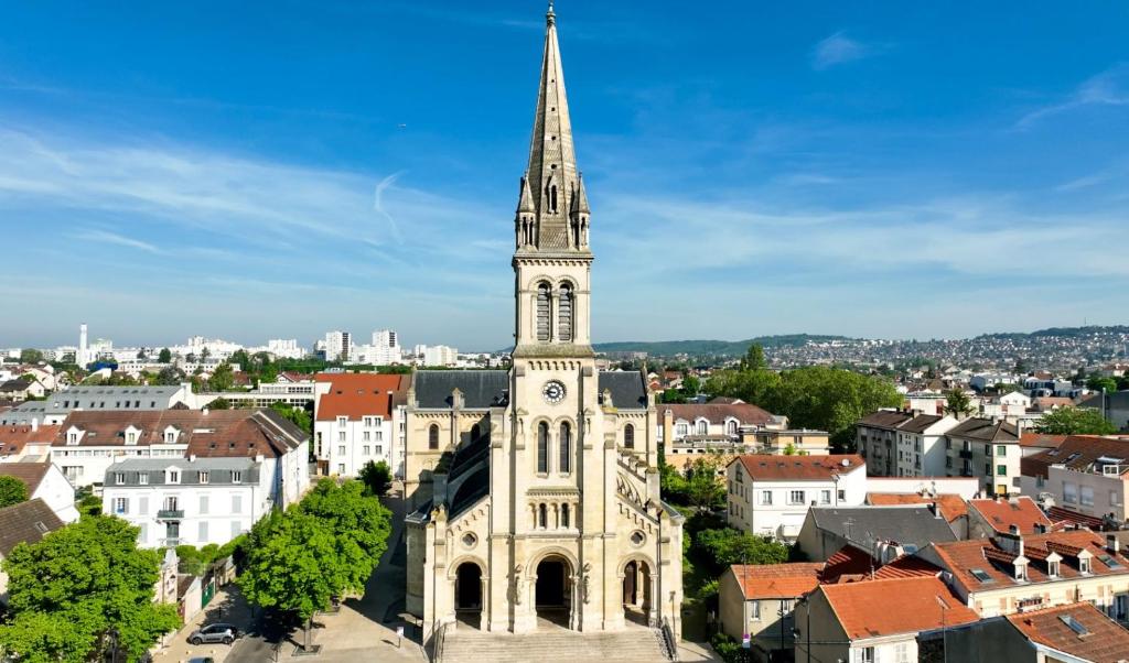 een hoge kerk met een torenspits bovenop een stad bij Le Berkane in Argenteuil
