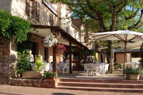 a patio with an umbrella and tables and chairs at Auberge Aux Portes de Conques in Saint-Cyprien-sur-Dourdou