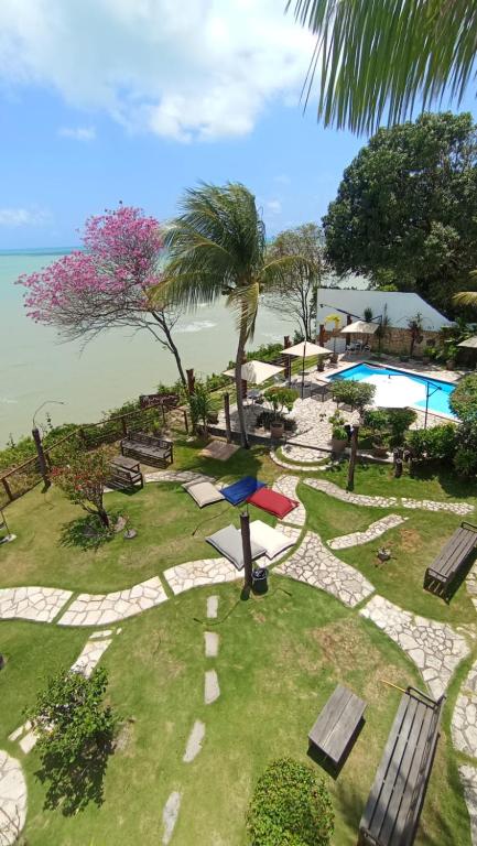a resort with a park with a pool and benches at Pousada Marajoara - Pipa in Pipa