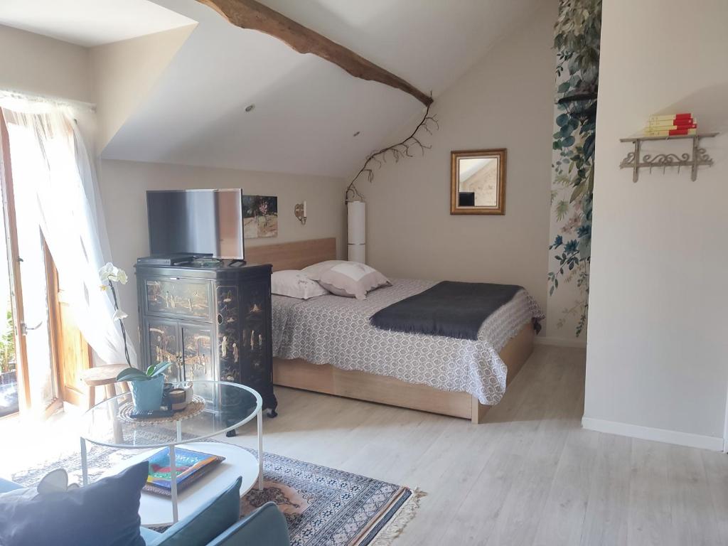 Vieille-Église-en-YvelinesLe petit grenier de la Quoiqueterie的带床和玻璃桌的卧室