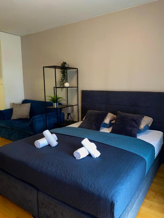 Un dormitorio con una cama azul y un sofá. en Maestral Living Studio Apartment, en Zagreb