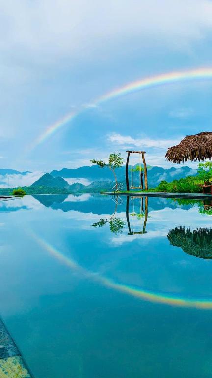 a rainbow over a body of water with a tree at Pu Luong Bản in Lũng Tiềm