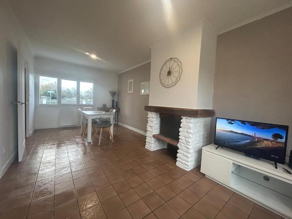 Una sala de estar con chimenea y televisión. en Maison chaleureuse à 2 minutes de la mer, en Colleville-Montgomery