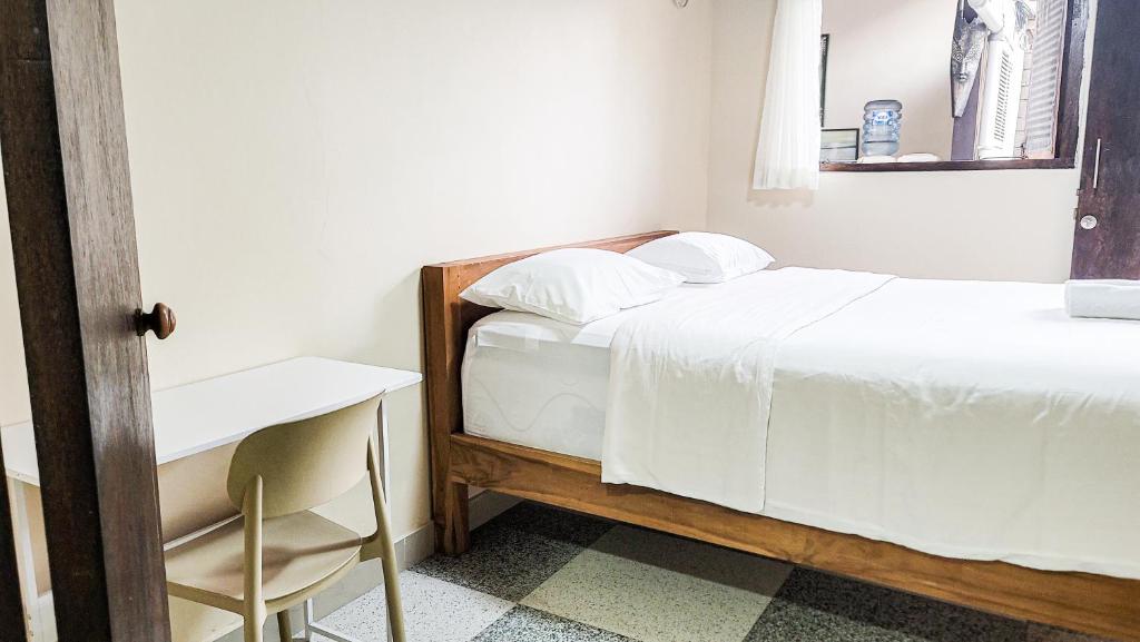a bedroom with a bed and a table and a chair at Capung Guesthouse in Jimbaran