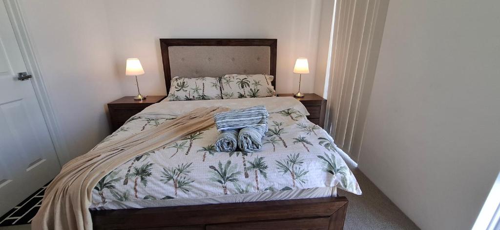 een kleine slaapkamer met een bed met 2 lampen bij Relaxing Lake side Master Room in Kelmscott