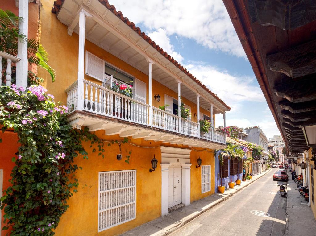 a yellow building with a balcony and flowers on a street at Casa Baloco in Cartagena de Indias