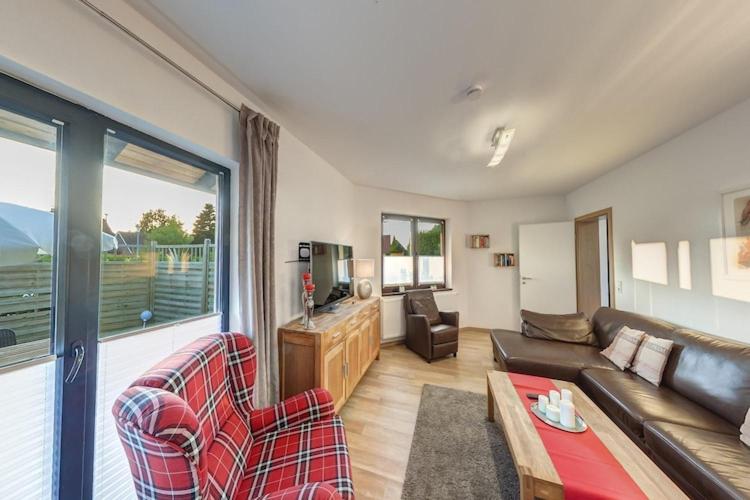 a living room with a couch and a tv at Großzügige Ferienwohnung für bis zu 9 Personen in Burhave