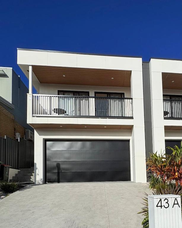 a garage door on a house with a balcony at Surfside Retreat-Stylish Escape in Bulli