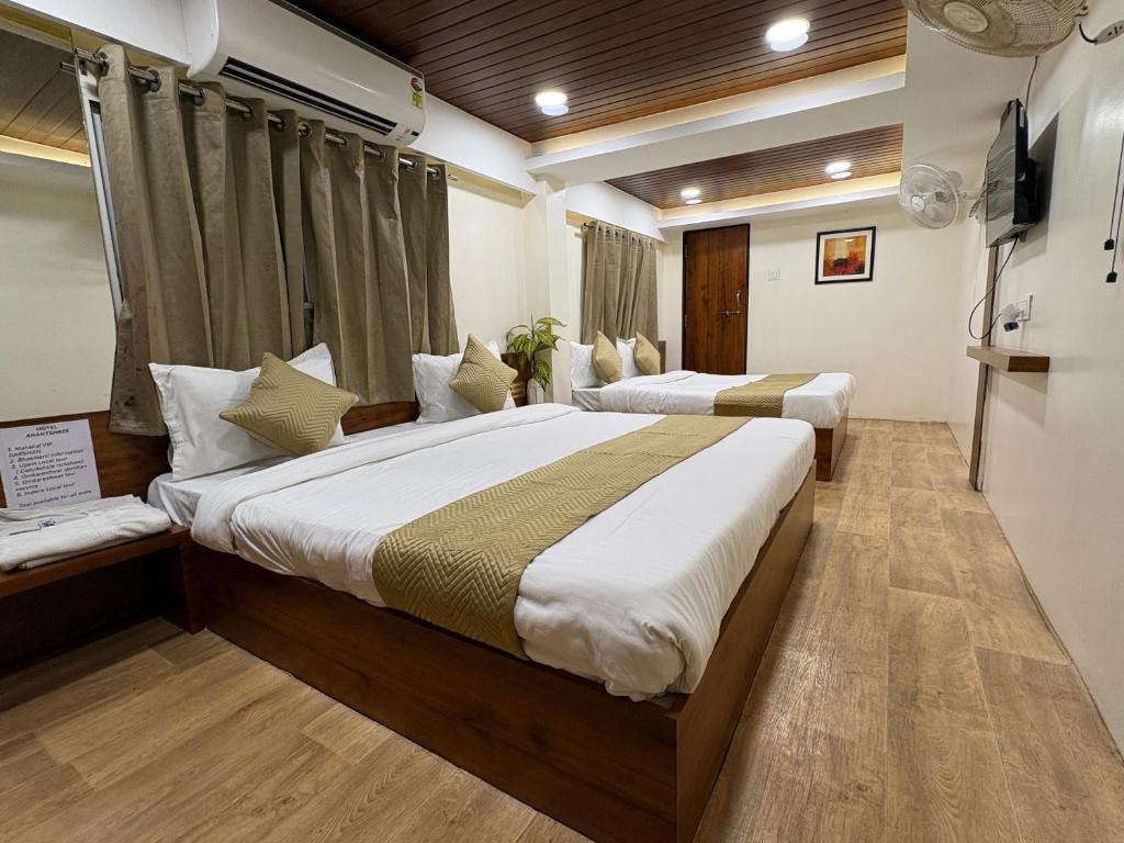 a hotel room with two beds and a television at Hotel Anantshree Inn Shree Mahakaleshwar Temple Ujjain in Ujjain