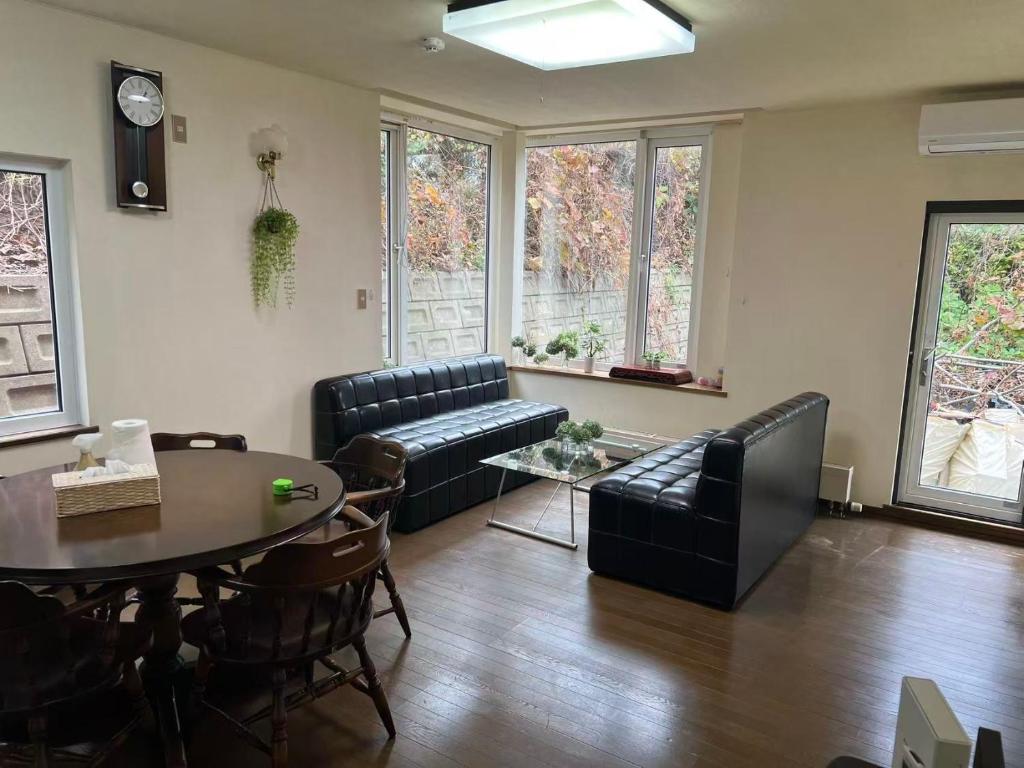 een woonkamer met een bank, een tafel en stoelen bij 青山ハウス in Otaru