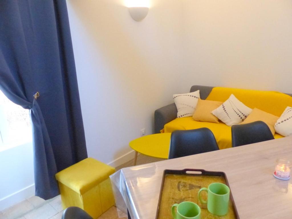 ein Wohnzimmer mit einem Tisch und einer gelben Couch in der Unterkunft Maison typique à Broût-Vernet avec animaux admis - FR-1-489-68 in Broût-Vernet