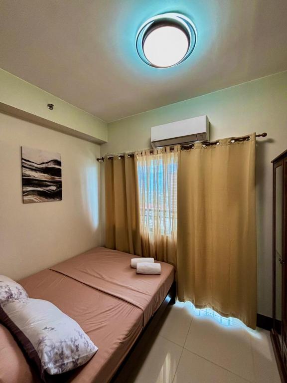 a small bedroom with a bed and a window at Fame Residence Tower 4 near Greenfield and Shaw MRT in Manila
