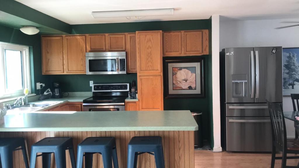 una cocina con armarios de madera y una isla de cocina con taburetes azules en your family home, en Aurora