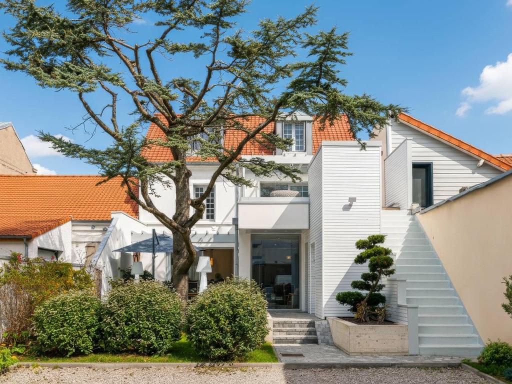 une maison blanche avec un arbre et des escaliers dans l'établissement Villa Centre ville du Touquet avec Climatisation et Wifi - FR-1-821-48, à Le Touquet-Paris-Plage
