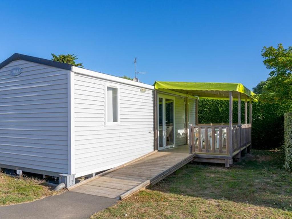 a white tiny house with a porch and a deck at Mobil-home Adapté PMR avec Terrasse à Notre-Dame-de-Monts - API-1-52-664 in Notre-Dame-de-Monts