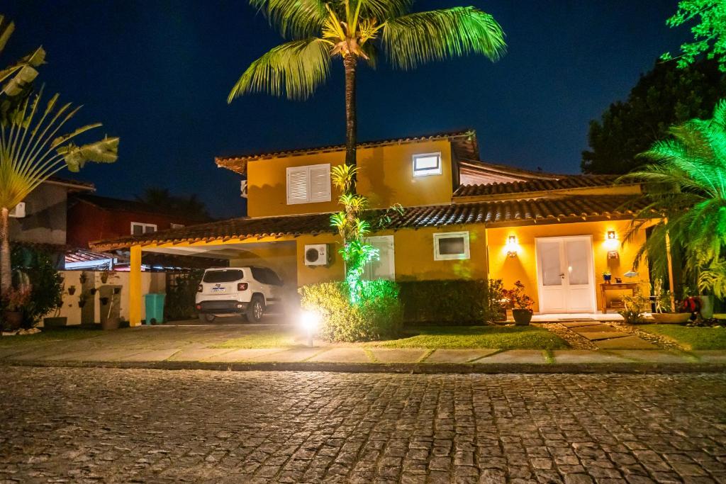 a house with a palm tree in front of a street at Casa Cajueiro - Arraial Dajuda - limpeza diária inclusa no preço para sua maior comodidade - localização excepcional em frente ao Eco Parque e poucos passos da Praia dos Pescadores in Arraial d'Ajuda