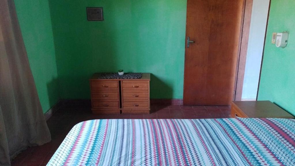 a green bedroom with a bed and a wooden dresser at Casa Argentina in Limpio