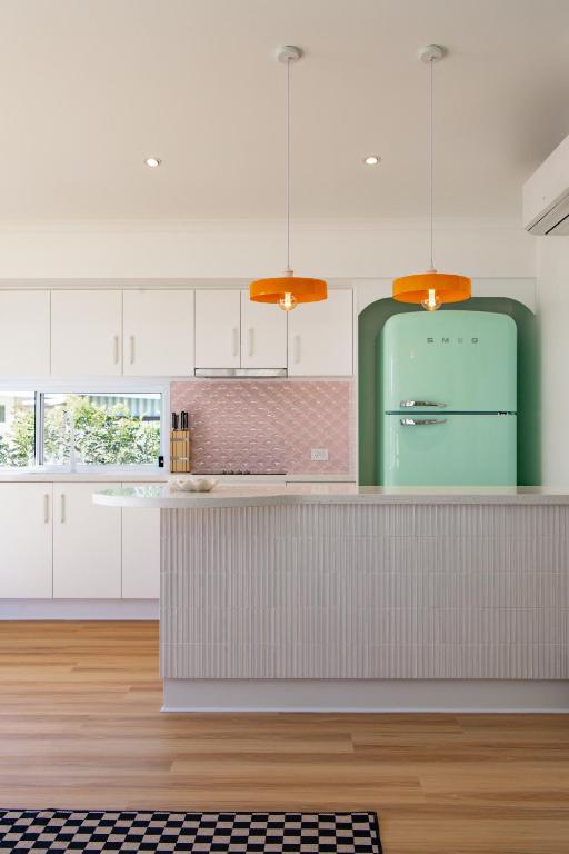 a kitchen with white cabinets and a green refrigerator at The Little Tropicana in Byron Bay