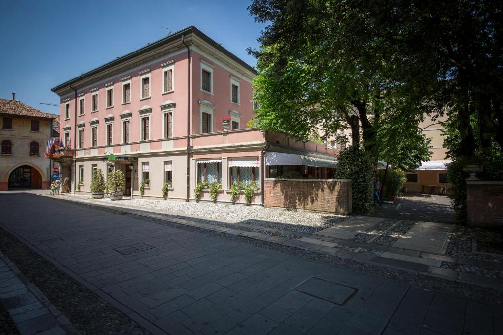 an empty street in front of a pink building at Hotel Spessotto in Portogruaro
