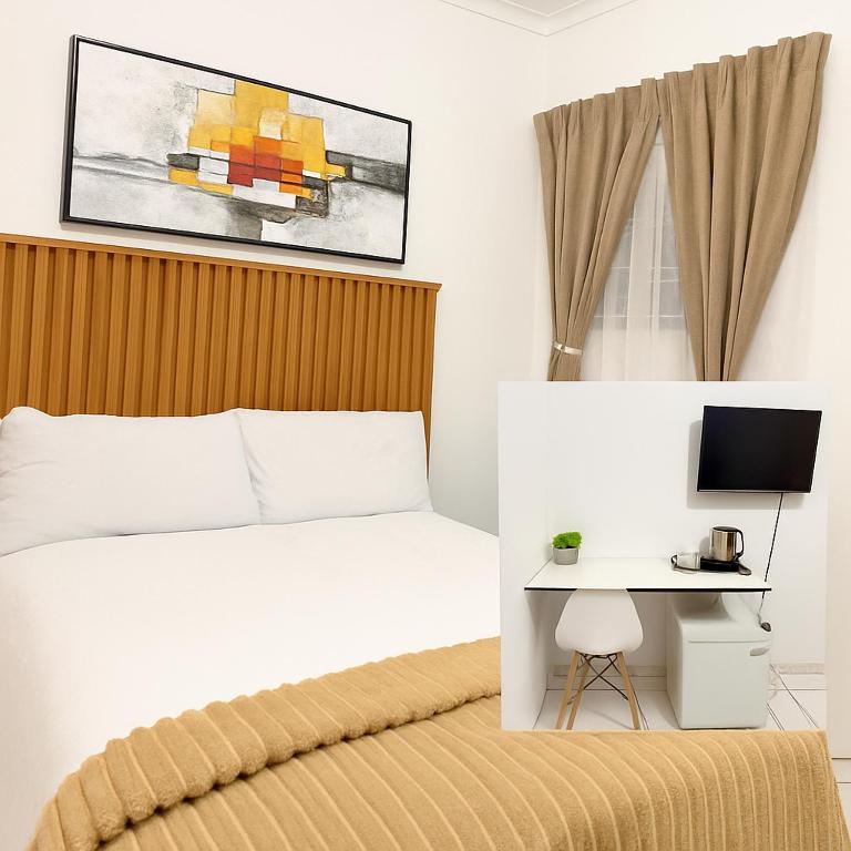 a bedroom with a white bed and a desk at Bonno Guest Suite in Gaborone
