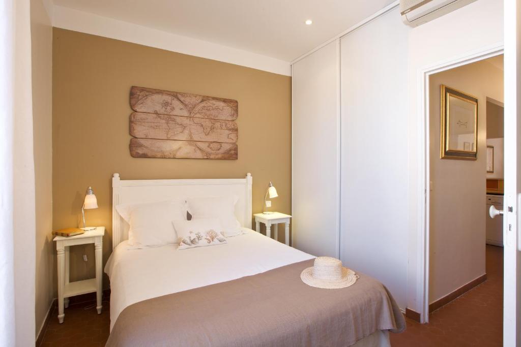 um quarto com uma cama branca com um chapéu em 15 Cours Massena em Antibes