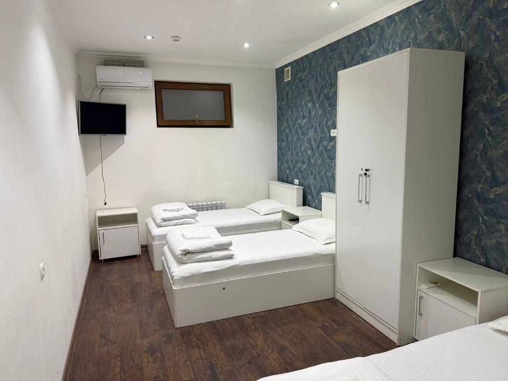 a room with three beds and a tv in it at Manija Hostel in Samarkand