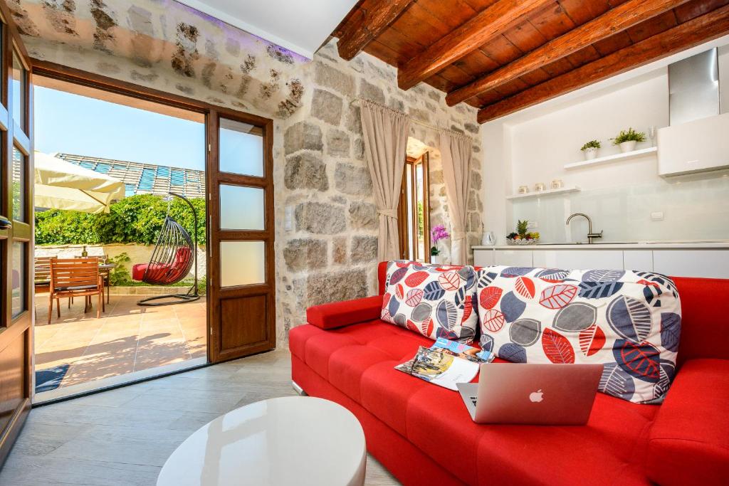 a red couch in a living room with a laptop at Apartments None and Nono in Cavtat