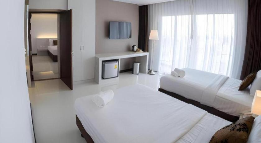 a hotel room with two beds and a television at Chaisaeng Villa in Sing Buri