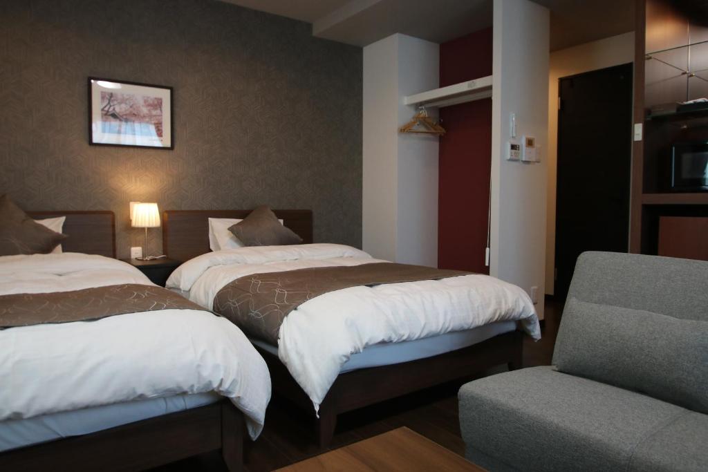 a hotel room with two beds and a chair at SA Inn 伊那ナイスロード in Wada