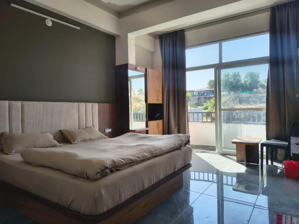 une chambre avec un grand lit et une grande fenêtre dans l'établissement Shree Vallabh Resort, à Nathdwara