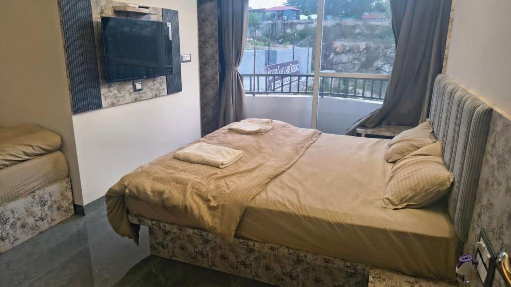a bedroom with a bed with a tv and a balcony at Shree Vallabh Resort in Nāthdwāra