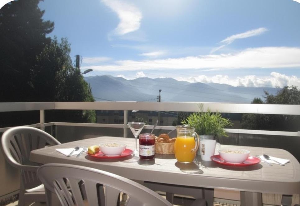 a table with breakfast food and drinks on a balcony at Le 1800 - Vue sur la chaîne des Pyrénées - Plein Sud in Font-Romeu
