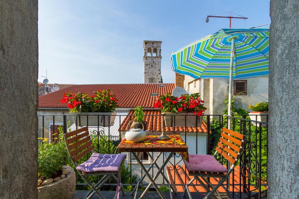 a table with chairs and an umbrella on a balcony at Rivabella Apartment in Poreč