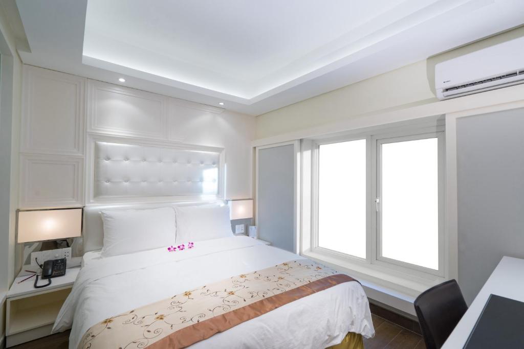 a bedroom with a white bed and a window at Empress Hotel Ho Chi Minh City in Ho Chi Minh City